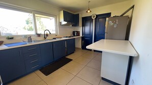 Una cocina moderna con armarios azul oscuro, encimera blanca, alfombra negra y refrigerador de acero inoxidable.