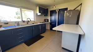 A modern kitchen with dark blue cabinets, a white countertop, a black rug, and a stainless steel refrigerator. - Oceana Suites Sueño Rural (Puerto Varas)