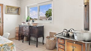 A kitchen with a window, wooden cabinets, a stove, and a table with a floral tablecloth.