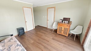 A room with wooden flooring, two white doors, a small cabinet with drawers, and a white chair.