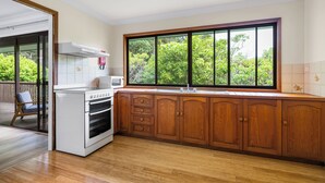 Una cocina con armarios de madera, una estufa blanca y un ventanal con vistas a zonas verdes.