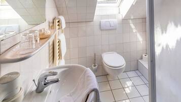 Un baño moderno con tragaluz, ducha y tocador con una toalla.