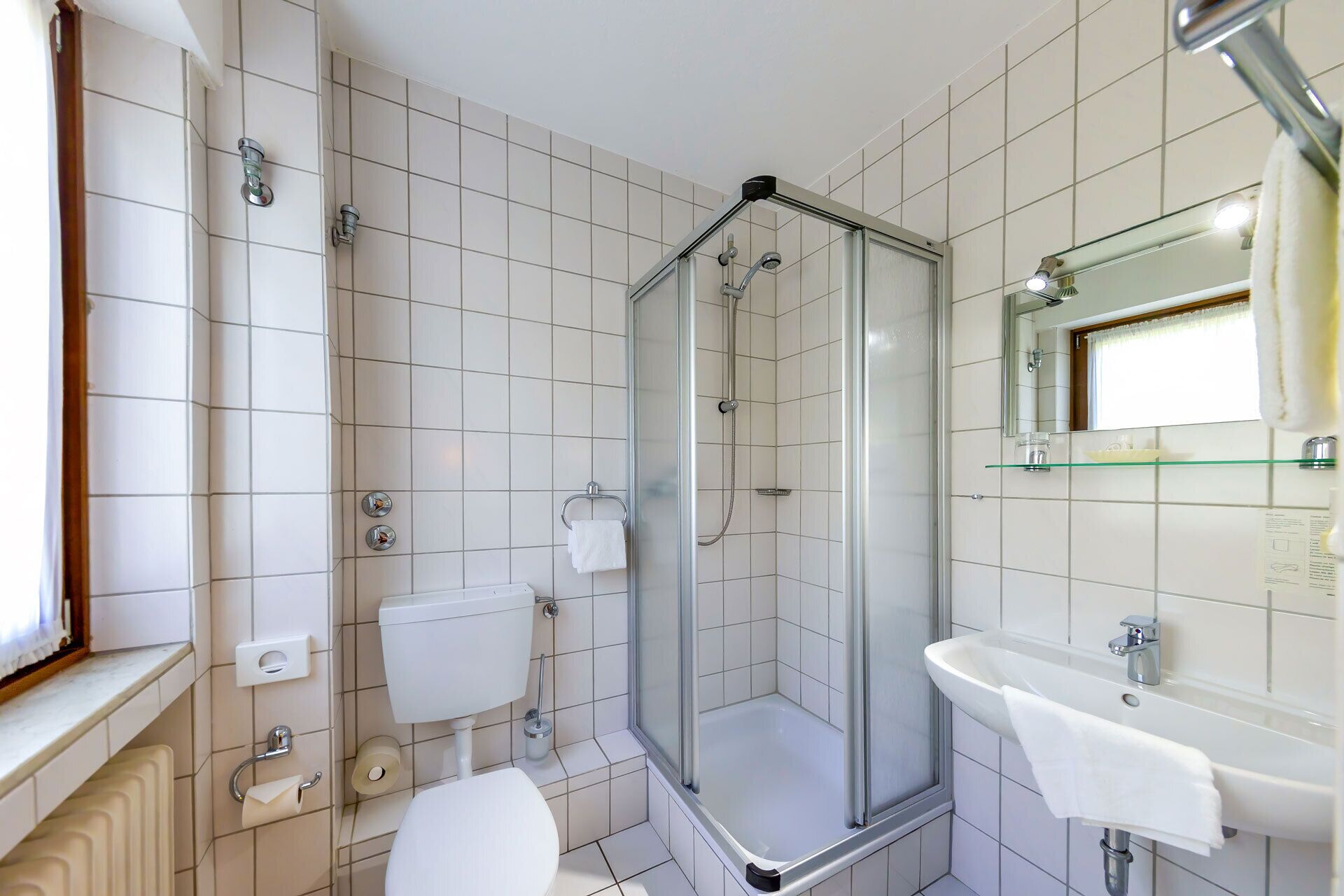 Un baño moderno con ducha de vidrio, inodoro, lavamanos y espejo.
