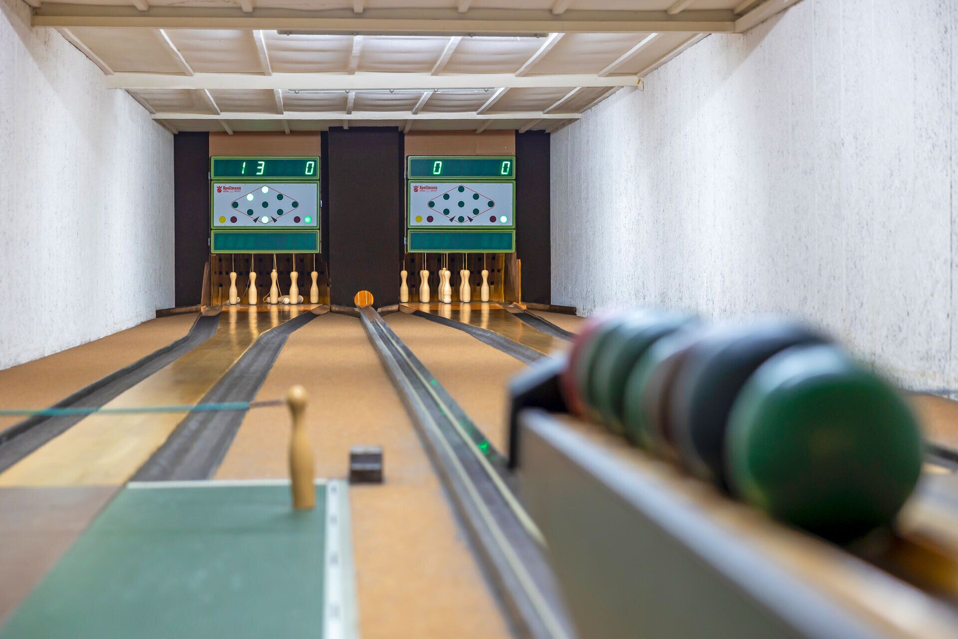 Una sala giochi a bowling con un tabellone che indica un punteggio di 13 a 0.