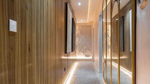 A modern hallway with wooden paneling, recessed lighting, and a patterned wall feature.