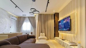 A modern living room with a large flat-screen TV, a sofa, a pool table, and a marble accent wall.