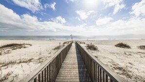 A wooden boardwalk leading to a beach with dunes and a flagpole in the distance. - Beach Club 1109 D (Gulf Shores)
