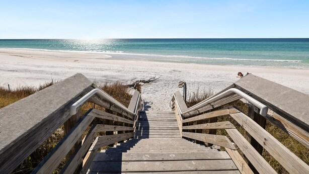 Eine Holztreppe führt zu einem Strand mit freiem Blick auf den Ozean.