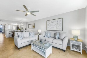 A modern living room with a white sofa set, a coffee table, and a ceiling fan. - The Somerset Solace | Pools, Tennis Courts & Gym (Marco Island)