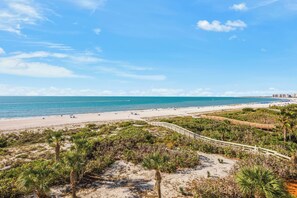 A beach with a wooden boardwalk, sandy dunes, and a clear blue sky. - The Somerset Solace | Pools, Tennis Courts & Gym (Marco Island)