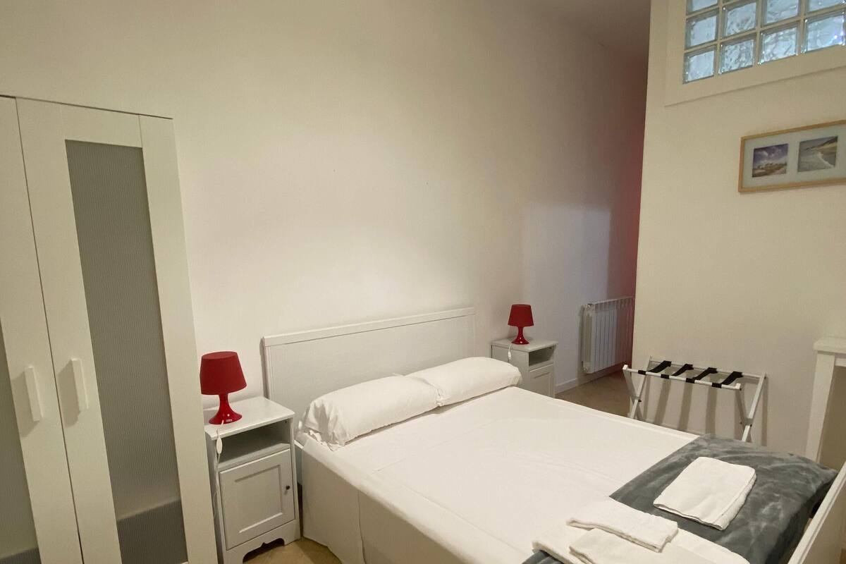 A bedroom with a bed, bedside tables, a wardrobe, and a window.