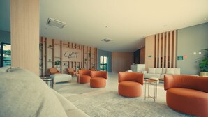 Moderni hotellin aula, jossa on keskeinen oleskelualue, vastaanottotiski ja suuri seinä, jossa on teksti ”CHAT”.