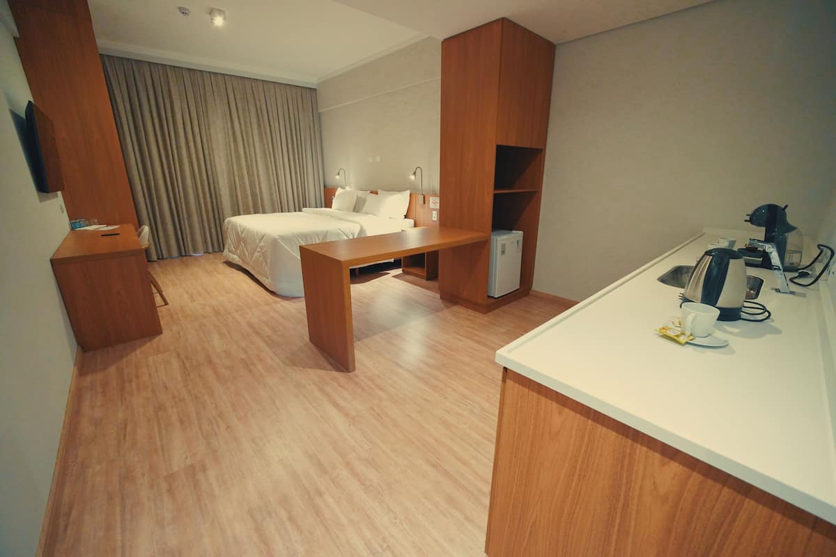Une chambre d’hôtel équipée d’un lit, d’une table de chevet, d’un bureau et d’un coin cuisine.