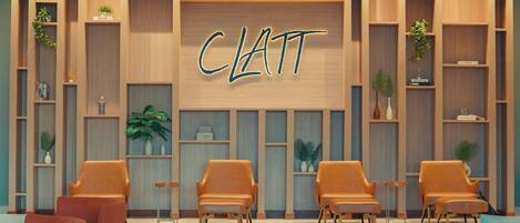 A modern interior with a central wall displaying the name 'CLATT' in illuminated letters, flanked by wooden shelving units with plants and decorative items, and several orange chairs arranged in the foreground.