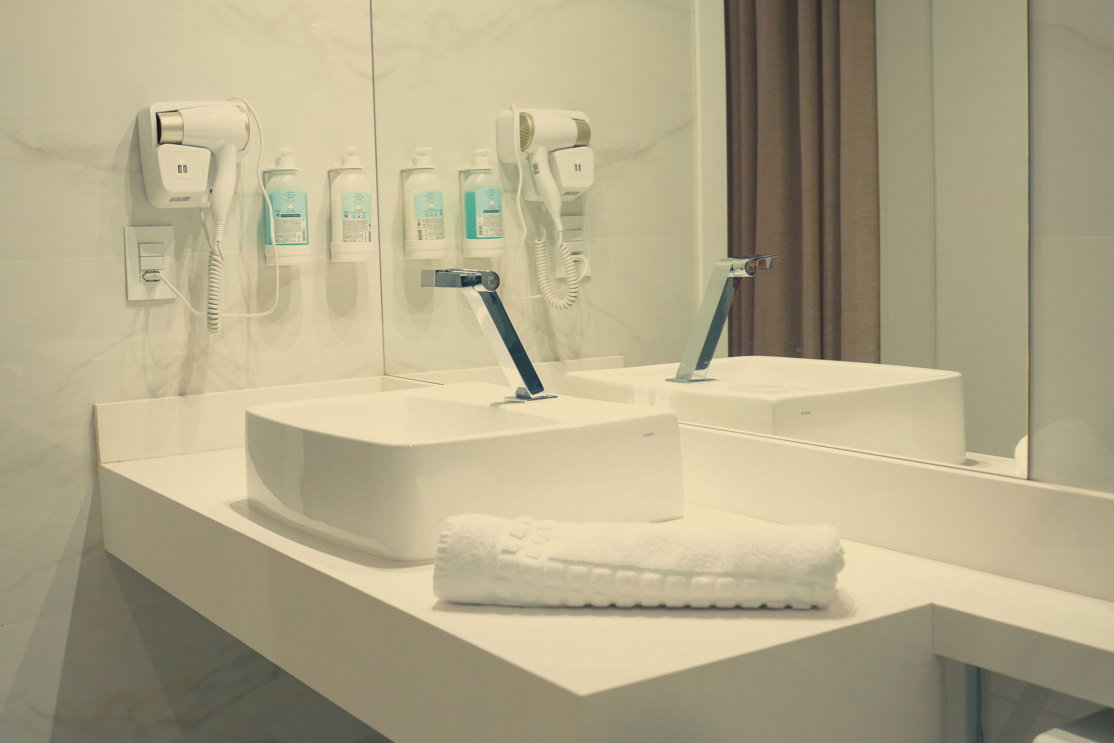 Un bagno moderno con due lavabi, un asciugacapelli e un asciugamano sul ripiano.