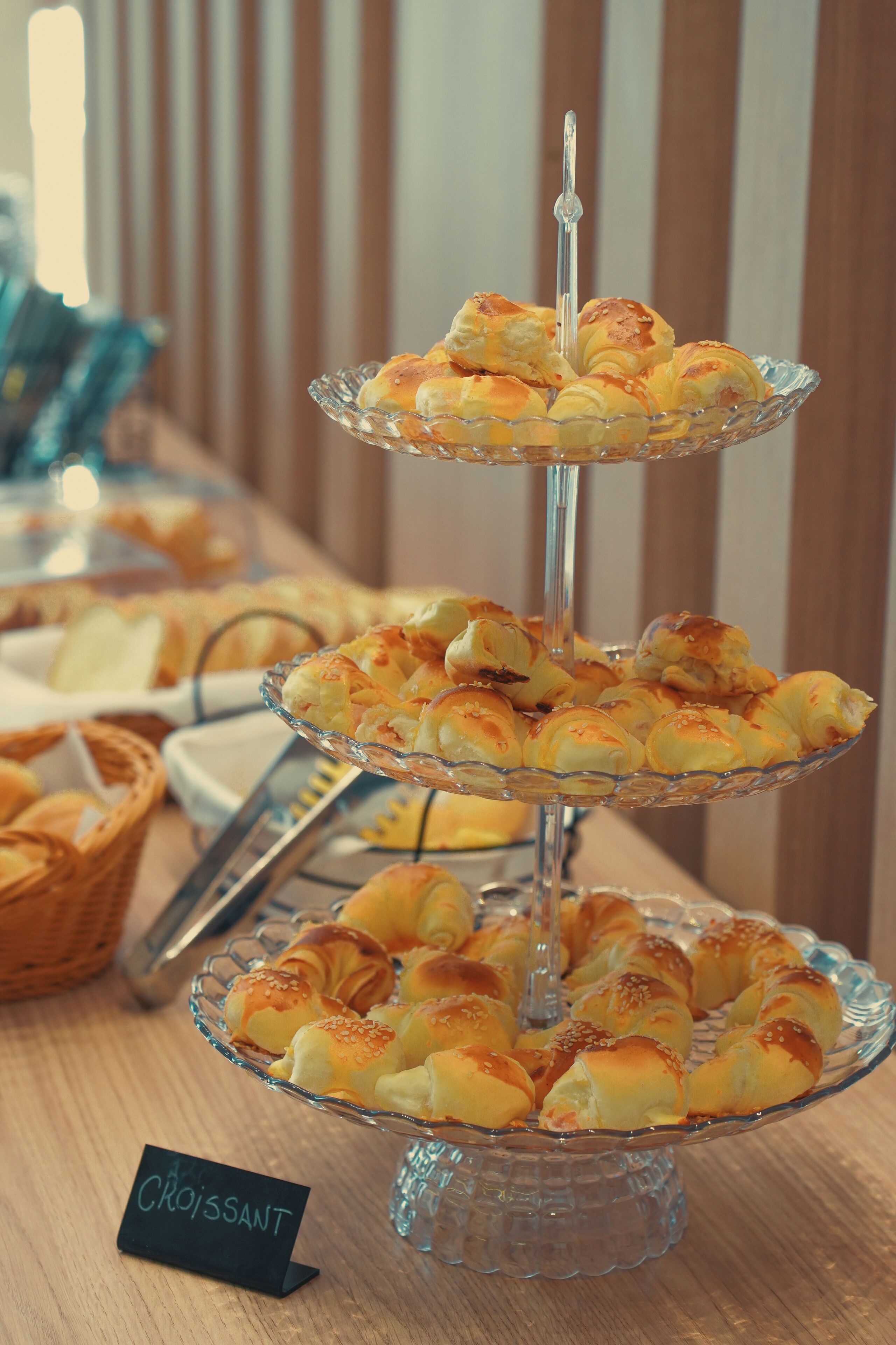 Useista tasoista koostuva lasinen esillepanoteline, jossa on croissantteja.