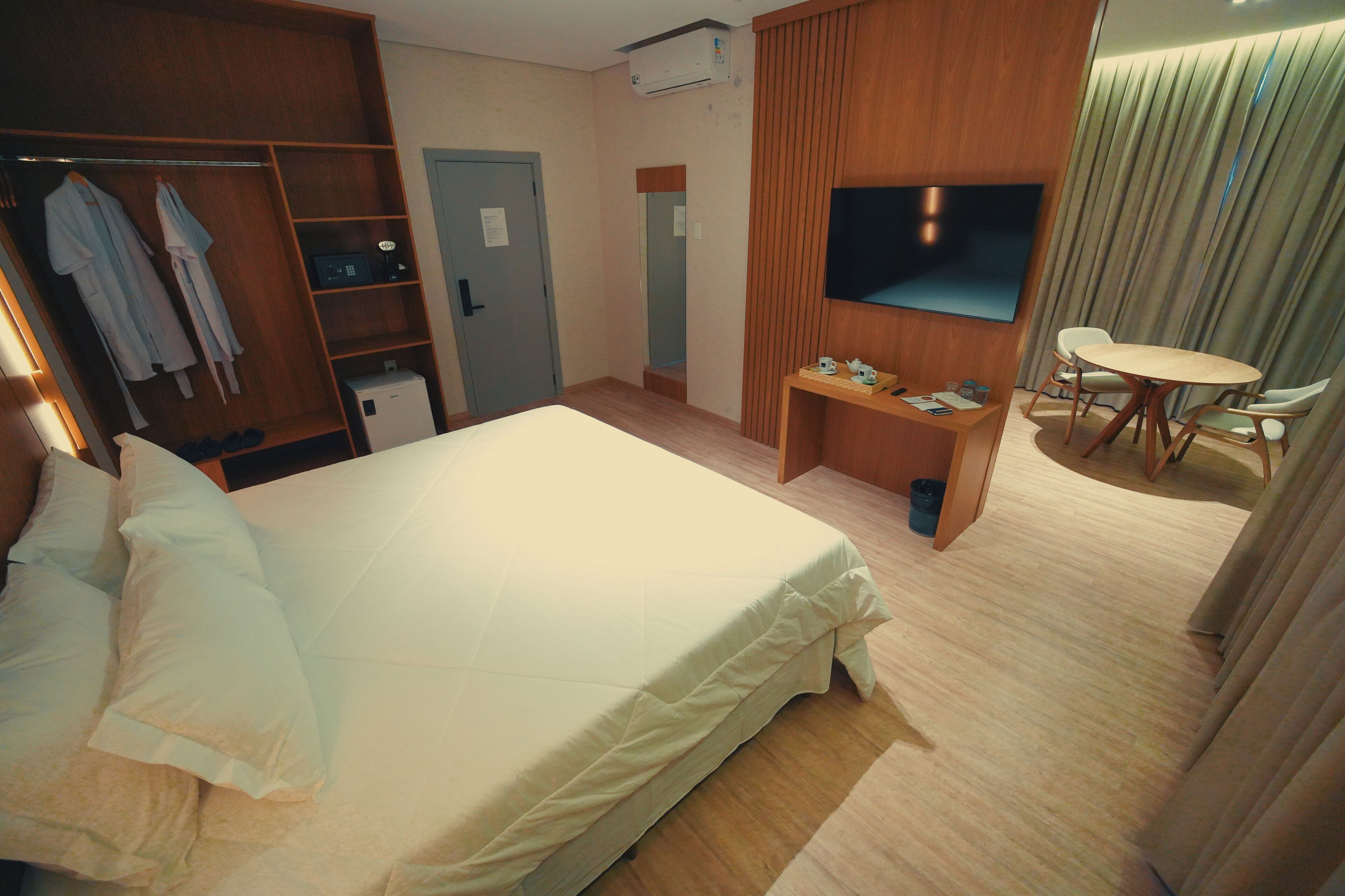 Une chambre d’hôtel comprenant un lit, une télévision, un bureau avec une chaise, une armoire et une porte de salle de bain.