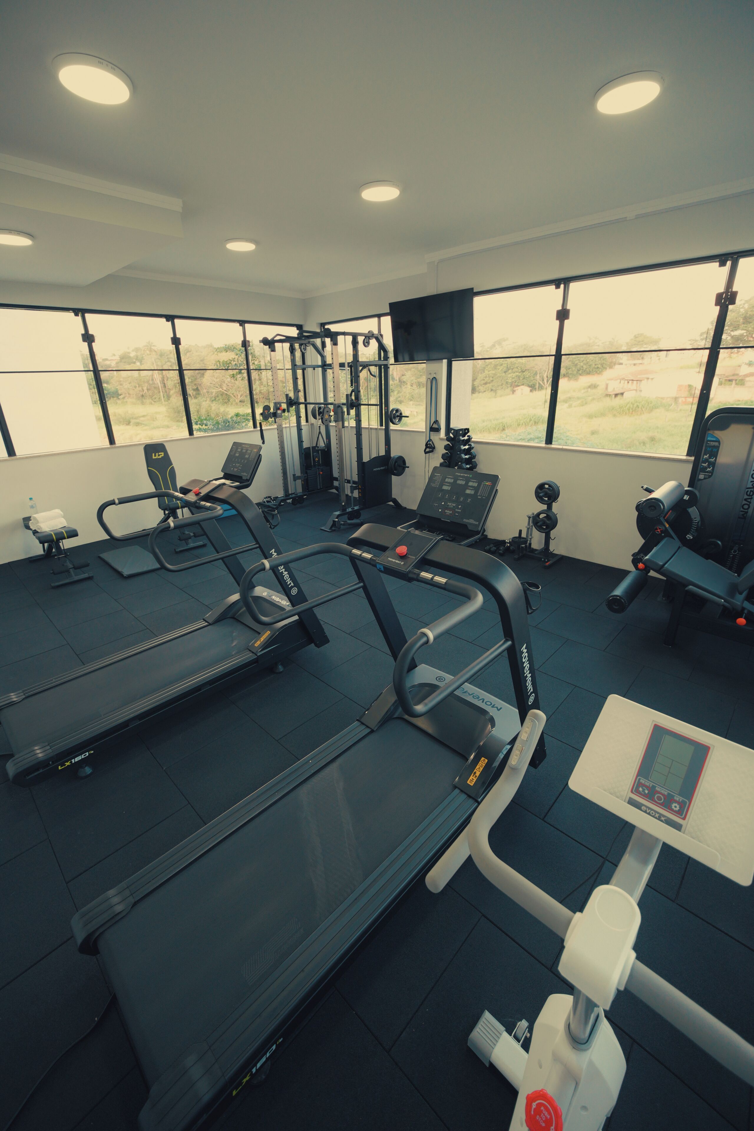 Et fitnesscenter med løbebånd, styrkemaskiner og et kontrolpanel.