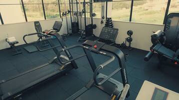 Et fitnesscenter med løbebånd, styrkemaskiner og et kontrolpanel.