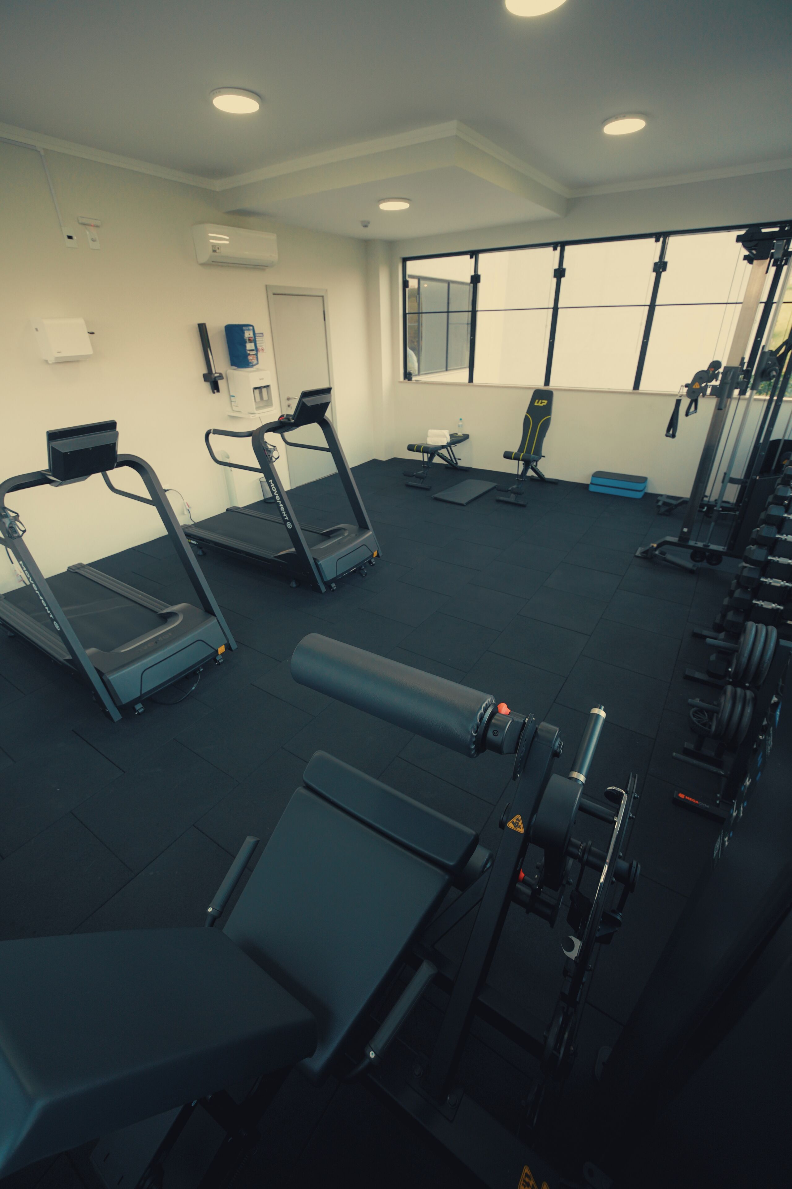 Un gimnasio con cintas de correr, máquinas de pesas y un banco.
