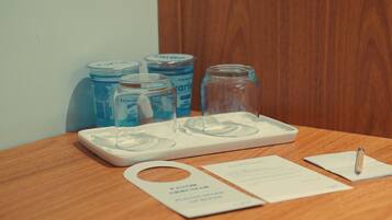 A wooden table with a tray holding two clear glasses, a pen, and a card.