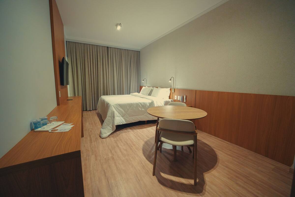 Une chambre d’hôtel avec un lit, un bureau, une chaise et une petite table.