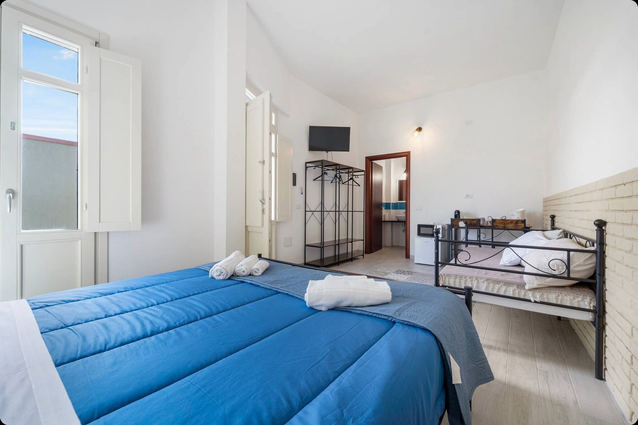 Een slaapkamer met een bed, een televisie, een kledingkast en een badkamer die door een open deur zichtbaar is.