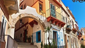 Un edificio a più piani con un ingresso ad arco in pietra, balconi e un cielo azzurro.