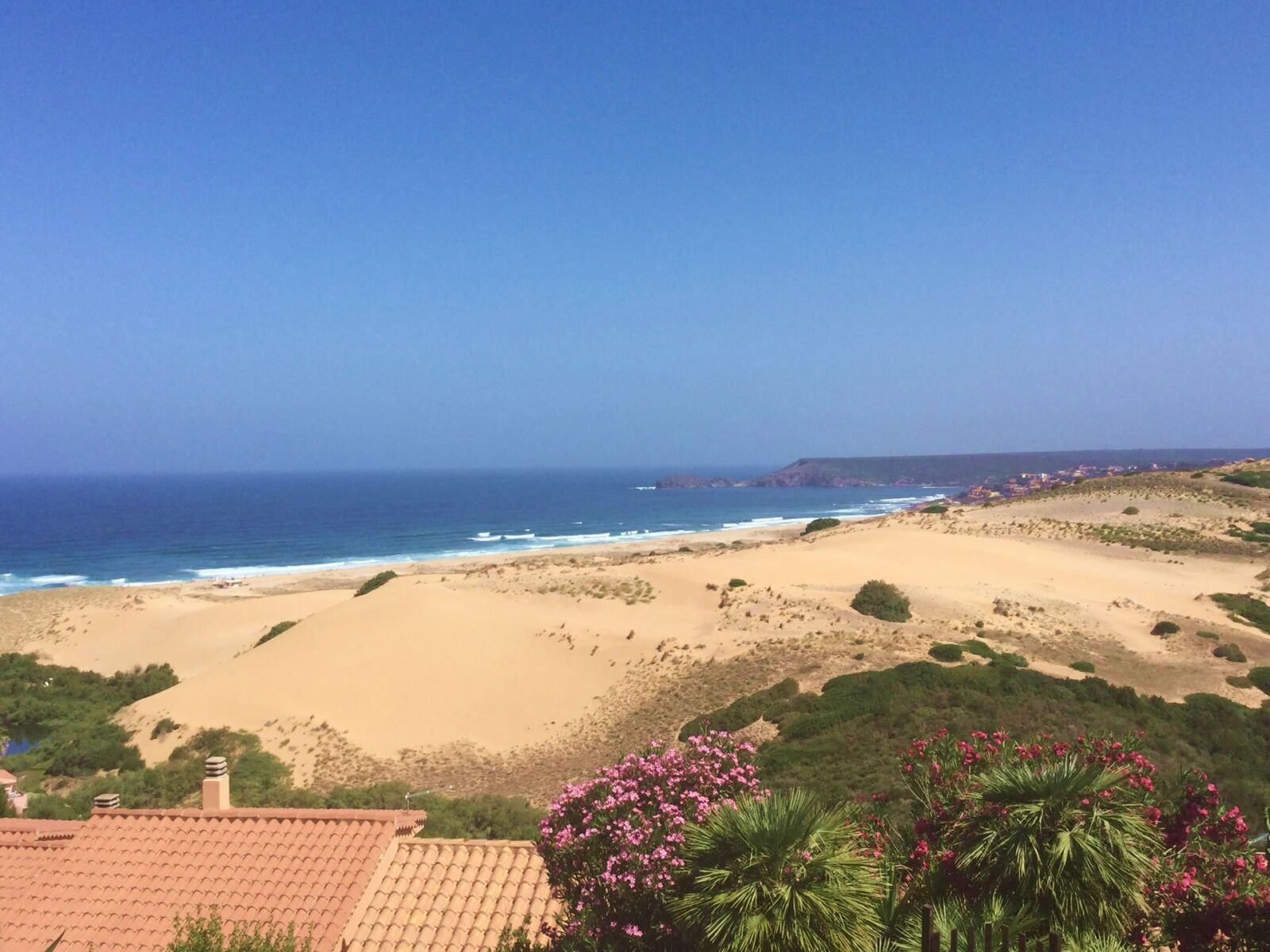 Un paisaje costero con playa, océano y acantilados lejanos.