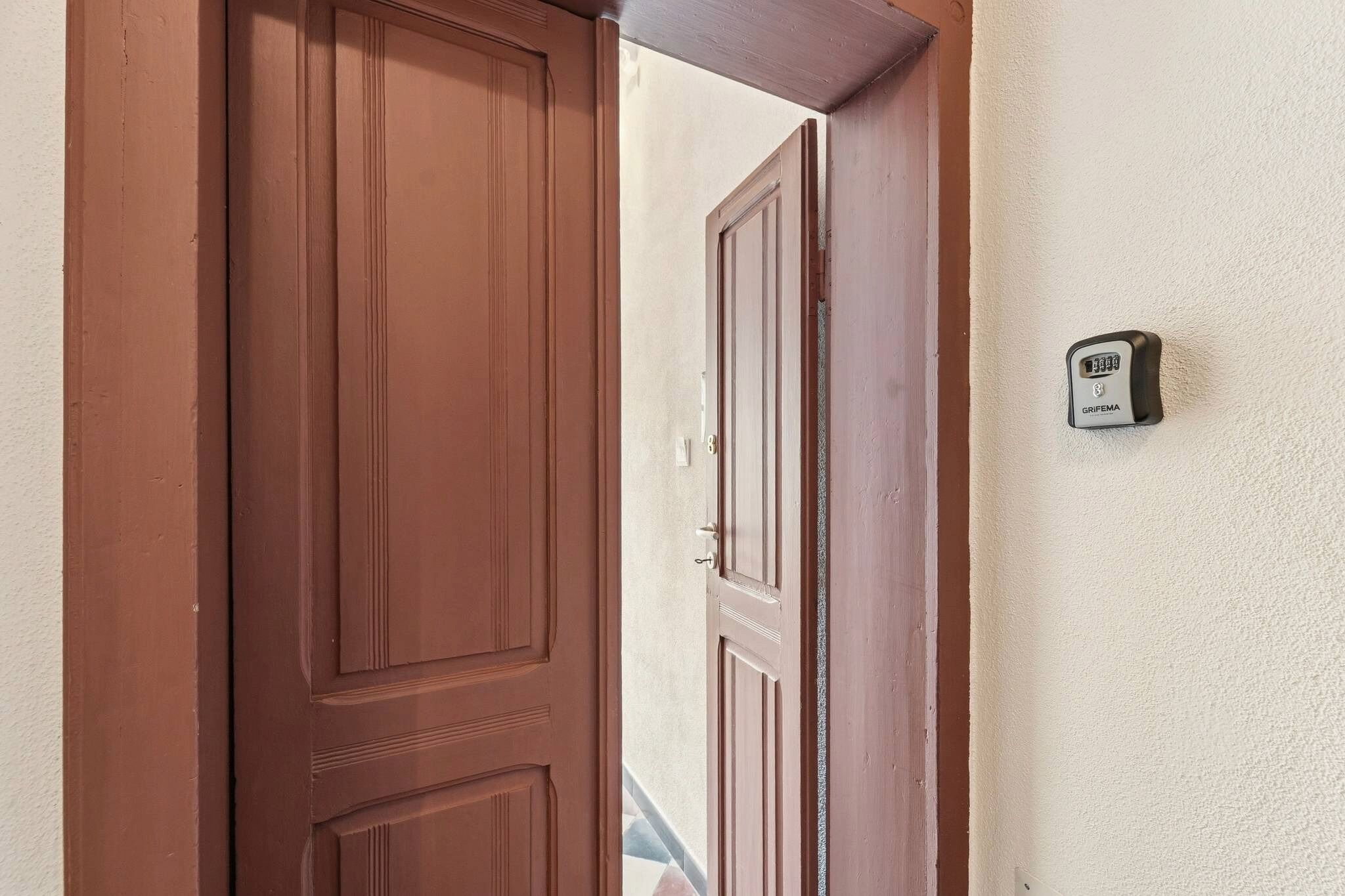 A brown door with a keypad lock and a wall-mounted device.