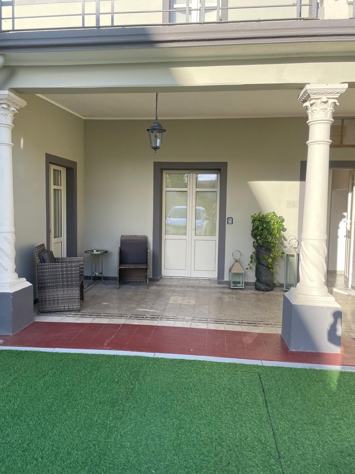 A covered entrance with a door, a bench, and a wicker chair.
