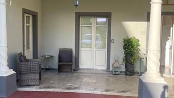A covered entrance with a door, a bench, and a wicker chair.