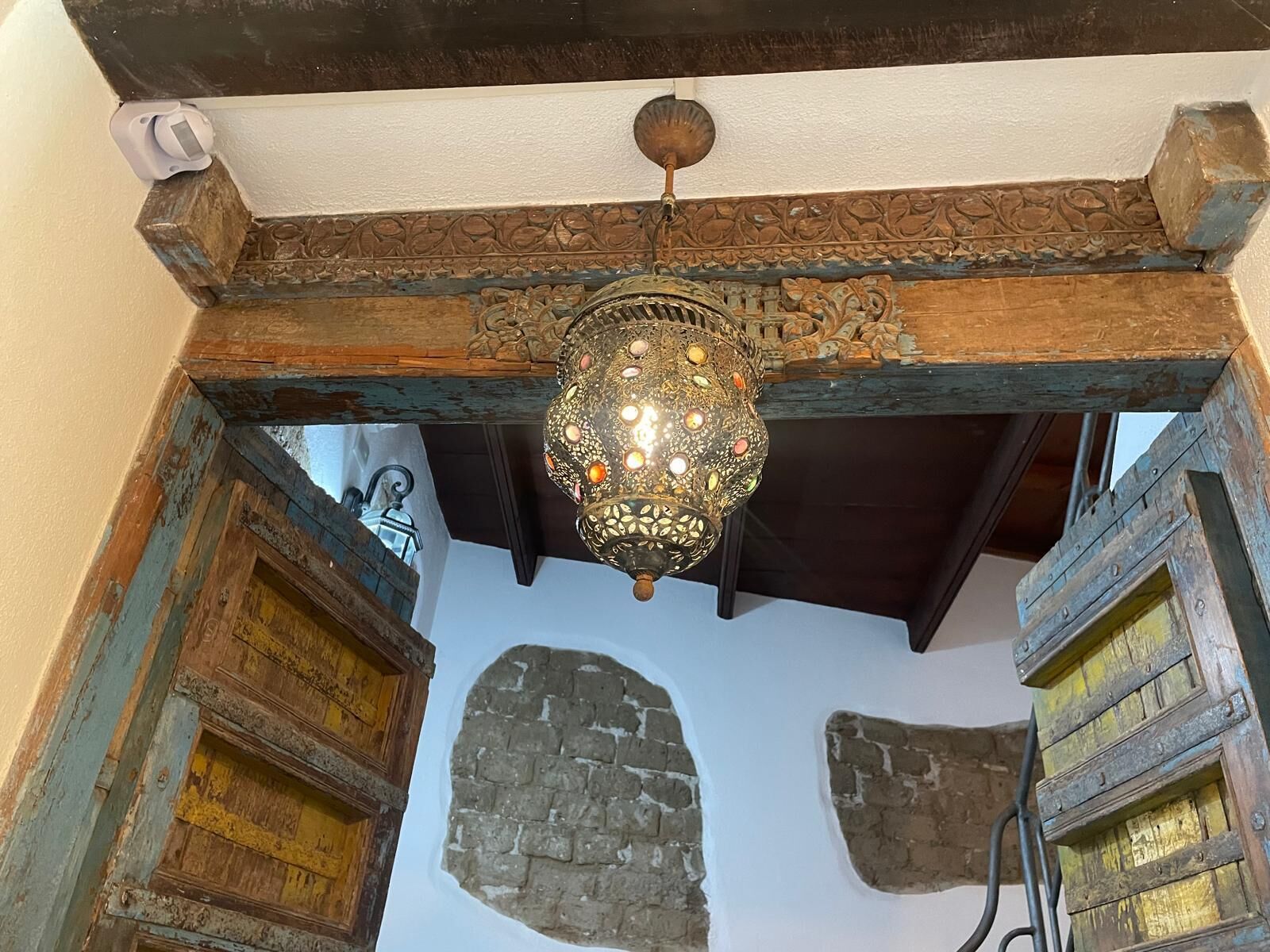 An ornate chandelier hanging from a wooden ceiling with intricate carvings.