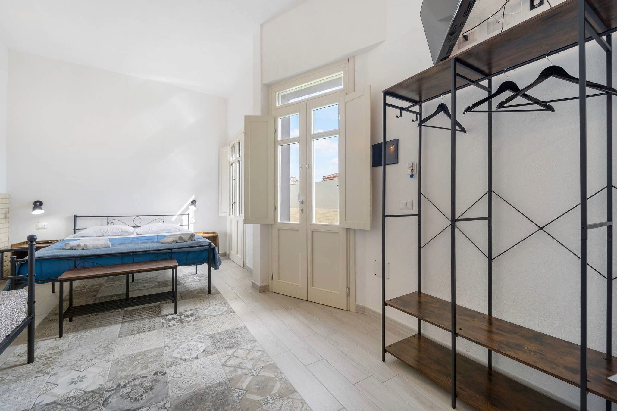 Ein Schlafzimmer mit einem Bett, einer Bank, einem Kleiderschrank und einem Fenster.