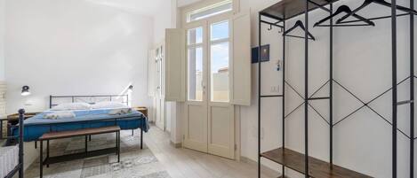 Ein Schlafzimmer mit einem Bett, einer Bank, einem Kleiderschrank und einem Fenster.