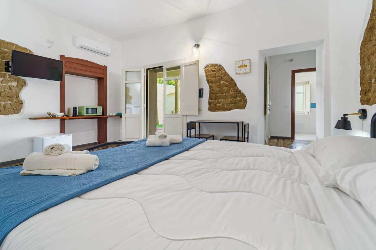 Ein Hotelzimmer mit einem großen Bett, einem Flachbildfernseher, einer Mikrowelle und einer Wand mit Steinverkleidung.