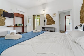 Una camera d'albergo con un letto grande, una televisione a schermo piatto, un forno a microonde e una parete decorativa in pietra.