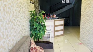 A reception area with a sofa, a potted plant, and a staircase in the background. - Eleon Hotel (Baku)