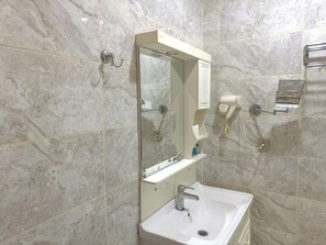 A bathroom with a marble wall, a sink, a mirror, and a towel rack. - Eleon Hotel (Baku)