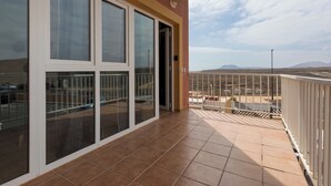 En balkon med store vinduer og udsigt over en parkeringsplads og et fjerntliggende landskab.
