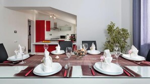 A dining area with a glass table set for six, red accents, and a view into a kitchen with red cabinets. - Heritage Pool Retreat Castinella - D1 (Pula)