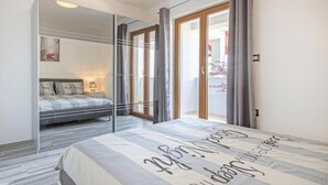 A modern bedroom with a bed, a nightstand, a mirror, and a sliding glass door leading to a balcony. - Heritage Pool Retreat Castinella - D1 (Pula)
