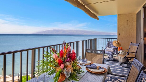 A balcony with a table set for dining, overlooking a body of water. - Panoramic Oceanfront View, Breathtaking Sunsets, Relax on Large Lanai (Lahaina)