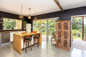 Una cocina moderna con una isla de madera, taburetes de bar y un amplio ventanal con vistas a zonas verdes.