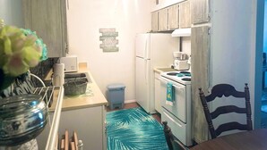 Una cocina compacta con refrigerador, estufa y un pequeño bote de basura.