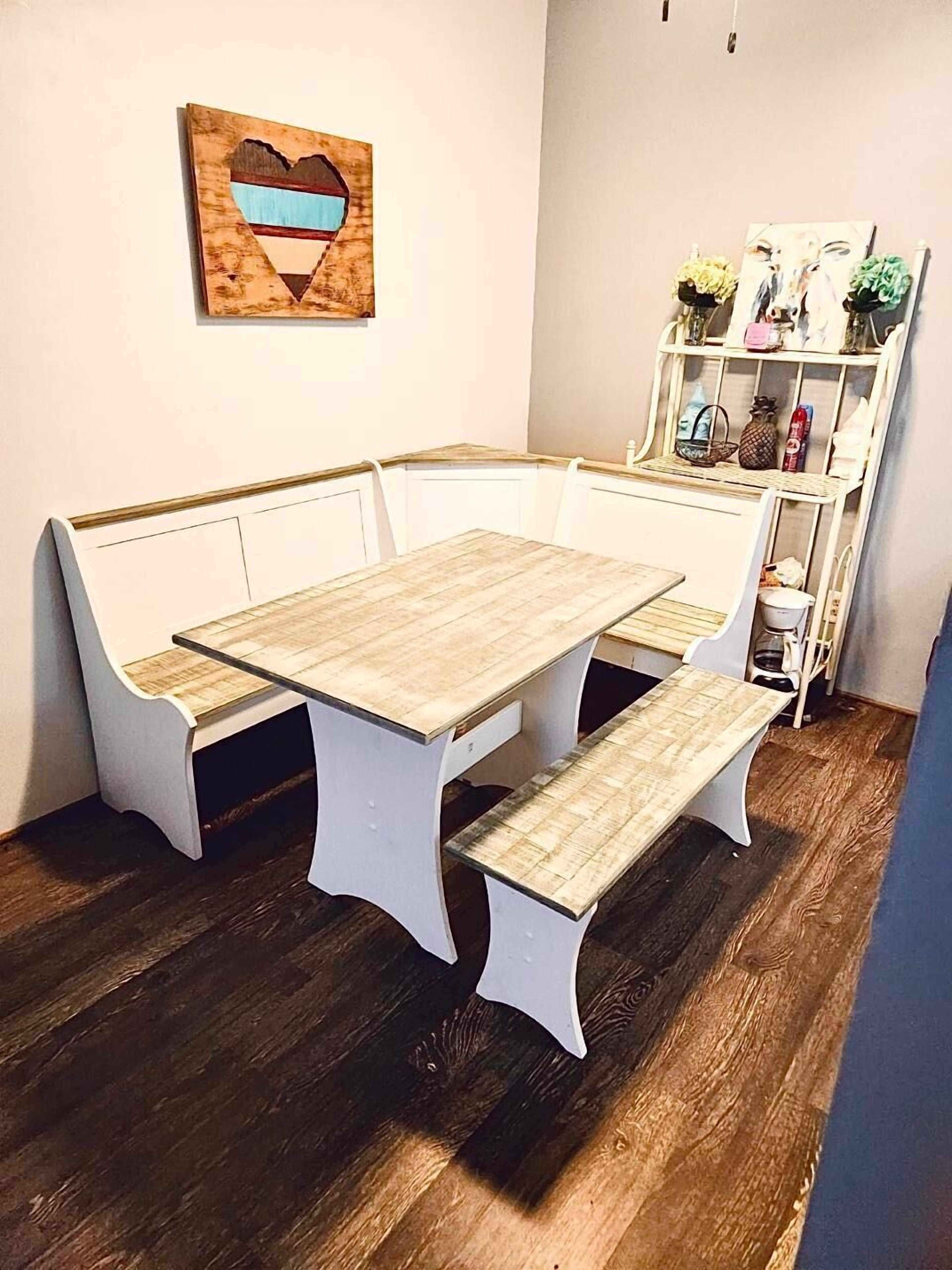 A corner dining area with a wooden table and white benches.