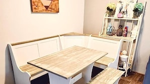 Un rincón comedor con mesa de madera y bancos blancos.