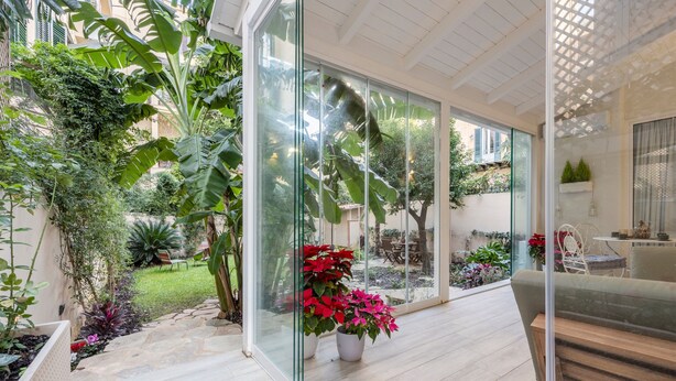 Een modern interieur met glazen wanden, een houten bank en potplanten.