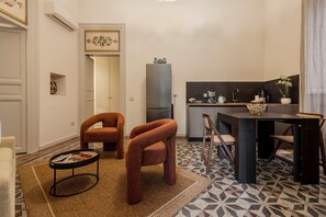 Ein kompakter Wohnbereich mit einer Küchenzeile, einem Essbereich mit Tisch und Stühlen sowie einer Sitzecke mit Sofa und Sesseln.