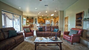 A spacious living room with leather sofas, a coffee table, and a view of a kitchen and dining area.